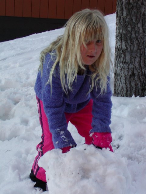 Sara rolling a snowball for another snowman